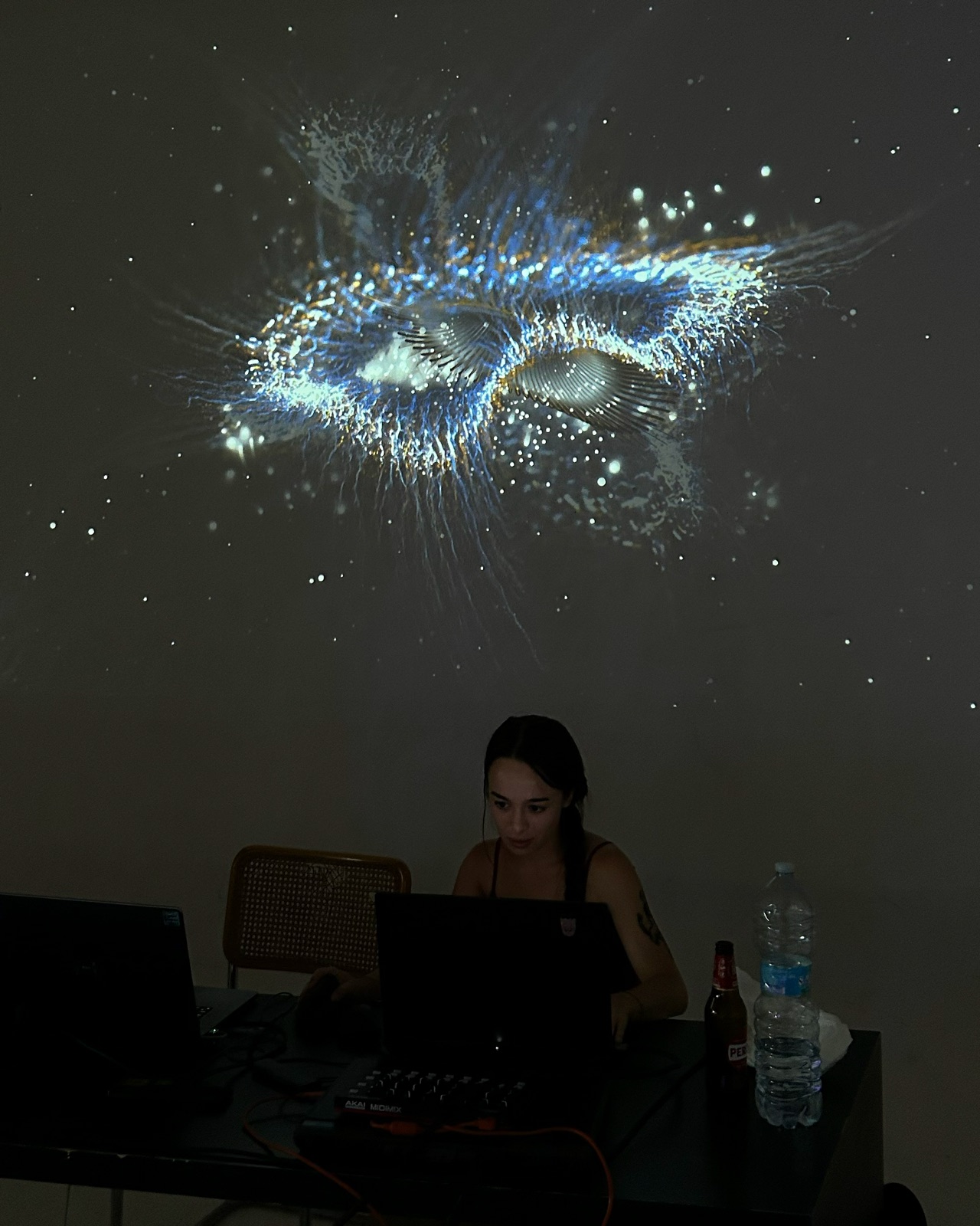 Malena Goya (VirDev) working in TouchDesigner, with her generative visuals projected behind her